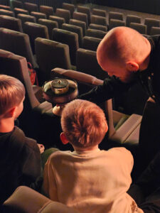 Kulturspatz Impressionen Medien: Mann zeigt Kindern Filmrolle im Kino