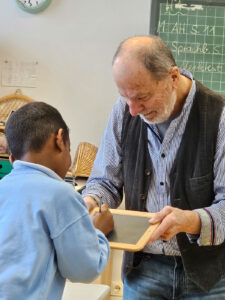 Mann zeigt einem Jungen etwas auf einer kleinen Tafel