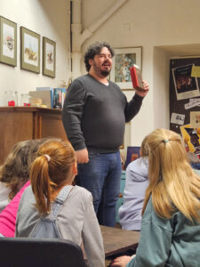 Mann spricht vor den Spatzen mit einem Buch in der Hand